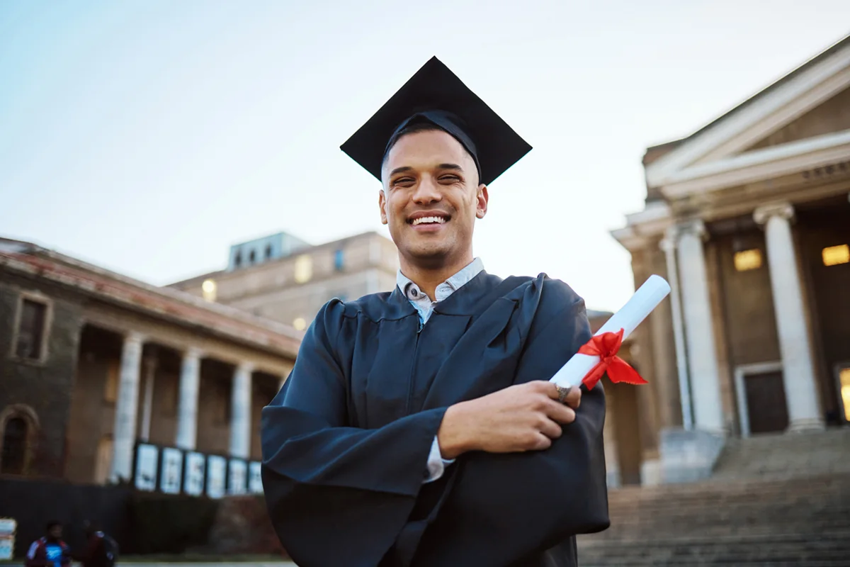 A recent graduate celebrating with a diploma on a university campus