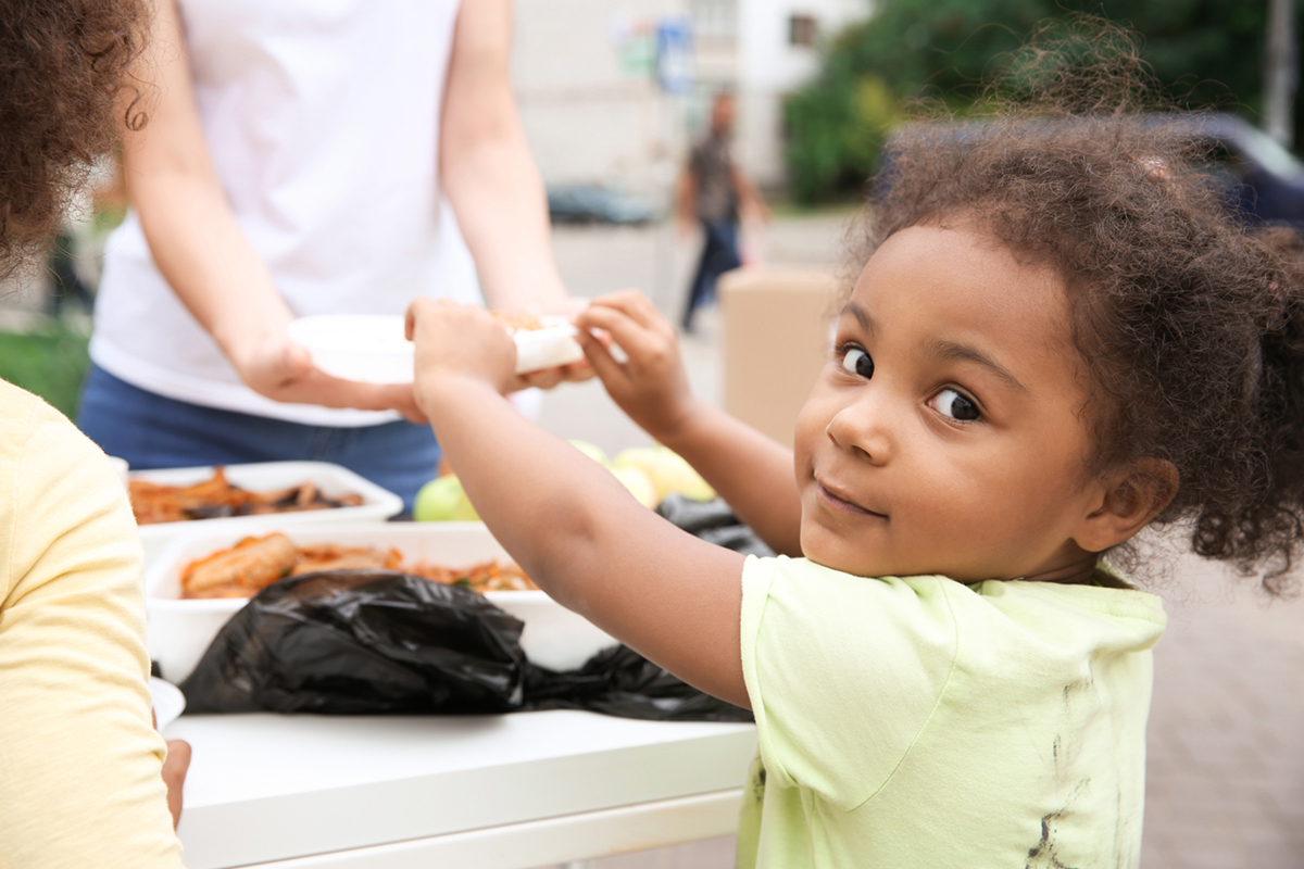 Volunteer serving food to a child at a community event.